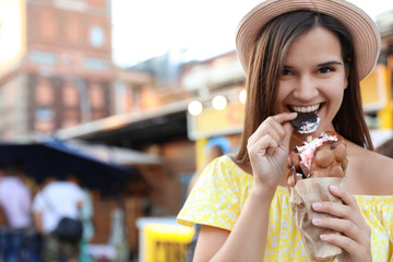 Wall Mural - Pretty young woman eating delicious sweet bubble waffle with ice cream outdoors