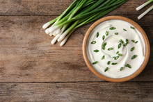 Bowl Of Fresh Sour Cream With Green Onion On Wooden Table, Flat Lay. Space For Text