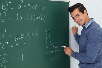 Young teacher drawing graph on chalkboard in classroom