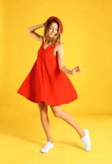 Sticker - Beautiful young woman in red dress dancing on yellow background