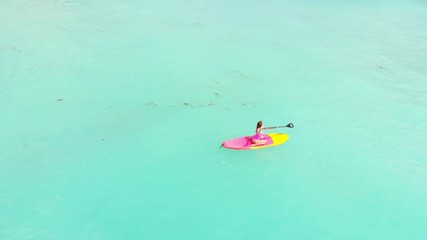 Wall Mural - Aerial view of woman on stand up paddle board in blue ocean.