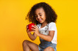 © Prostock-studio - Pretty girl holding red apple over yellow studio background