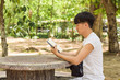 © banphote - Feeling tired. Young man holding book sitting on bench in the park and keeping eyes closed