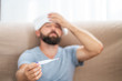 © Juliaap - High temperature concept. Man feels badly ill. How to bring fever down. Cold symptoms and causes. Sick man with flu. Man hold thermometer. Measure temperature. Break fever remedies.