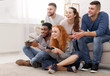 © Prostock-studio - Diverse friends playing video games, sitting on floor at home