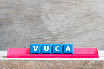 Wall Mural - Tile letter on red rack in word VUCA (abbreviation of Volatility, uncertainty, complexity and ambiguity) on wood background