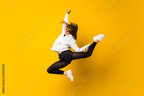 Fotomural Young woman jumping over isolated yellow wall