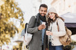 © kite_rin - Beautiful happy couple using smartphone. Young joyful smiling woman and man looking at mobile phone in a city in autumn.  Technology, travel, tourism, students concept