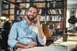 © Friends Stock - Happy to hear you Young bearded businessman in formal wear talking with client by phone and smiling while sitting in modern office