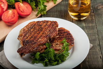 two pieces of of grilled pork with herbs on a paper on an old table top view horizontal close-up