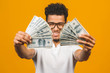 © denis_vermenko - Winner! Young rich african american man in casual t-shirt holding money dollar bills with surprise isolated over yellow wall.