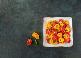 Wall Mural - salad of fresh red and yellow tomatoes with basil on a dark background