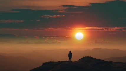 Wall Mural - the male standing on a mountain top against the bright sunrise. time lapse