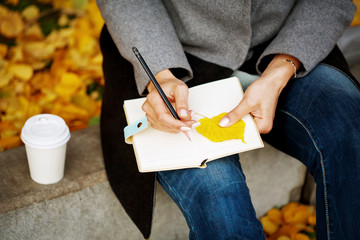 Woman`s hands close-up holding paper notebook and pencil