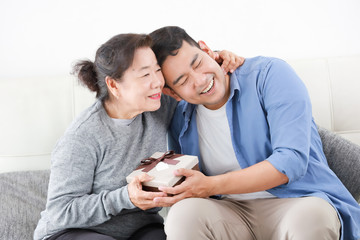 Asian Son give some present box to mother in living room smile and happy face in mother day