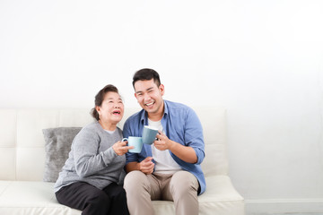 Wall Mural - Asian senior grand mother and son drinking coffee and talking happy and smile face in living room