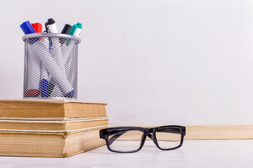 Wall Mural - White board, books, glasses and markers in the stand on the table. Copy space.