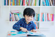 © Creativa Images - Happy little boy reading a book in the library
