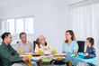© Creativa Images - Three generation family chatting at a dining table