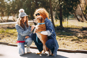 Wall Mural - Beautiful girls in a park. Stylish women in a jeans jacket. Ladies with a dog. Mother with a daughter