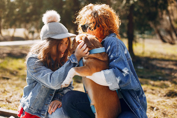 Wall Mural - Beautiful girls in a park. Stylish women in a jeans jacket. Ladies with a dog. Mother with a daughter