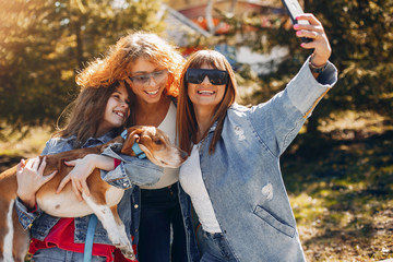 Wall Mural - Beautiful girls in a park. Stylish women in a jeans jacket. Ladies with a dog. Mother with a daughter