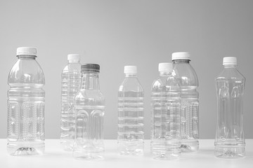 Plastic bottles in various shapes and sizes on white table and background