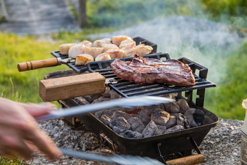 Steak and Scallops grilling on a hibachi as hot charcoal develops smoke and flames on a summer night