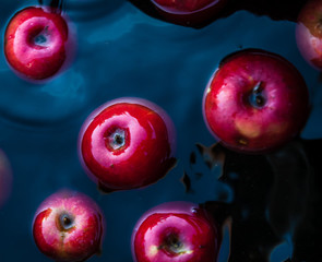 Wall Mural - Red juicy apples in the water in a bucket. Trending dark retro background. Concept, rich harvest. Top view.