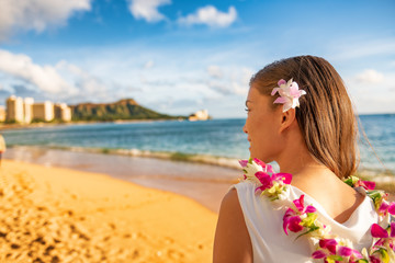 Hawaii woman wearing lei flower necklace and hair accessory on beach sunset for luau party or honeymoon wedding in Waikiki beach, Honolulu, holiday travel.