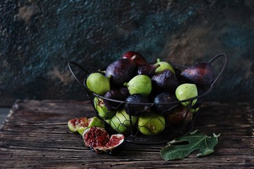 Wall Mural - figs Different sorts  in a basket on a dark background. Large, small purple figs and white figs