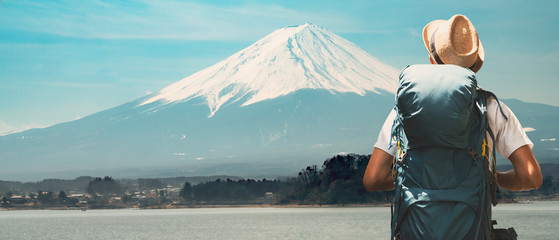 Young asian traveler with backpack in the Fuji Mountain. Hiking Fujisan volcano at Kawaguchiko lake, Japan. Backpacker standing and looking at the Mount Fuji in Japan. 