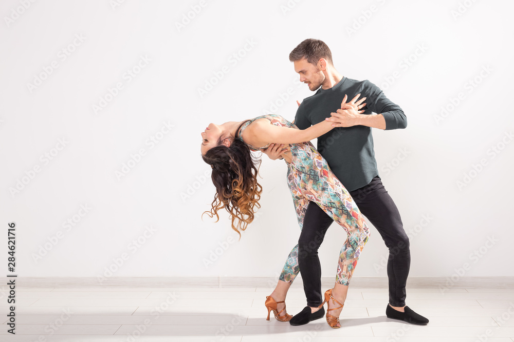 Young couple dancing social latin dance bachata, merengue, salsa. Two elegance pose on white background - obrazy, fototapety, plakaty 