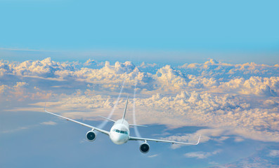 Aircraft flies high over the city and and sea coast -  White passenger airplane in the clouds at sunset - Travel by air transport