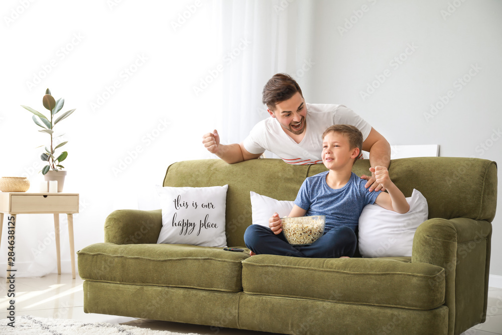 Father with son watching sports on TV at home
