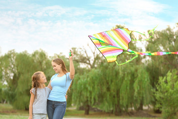 Poster - Young woman with little daughter flying kite outdoors