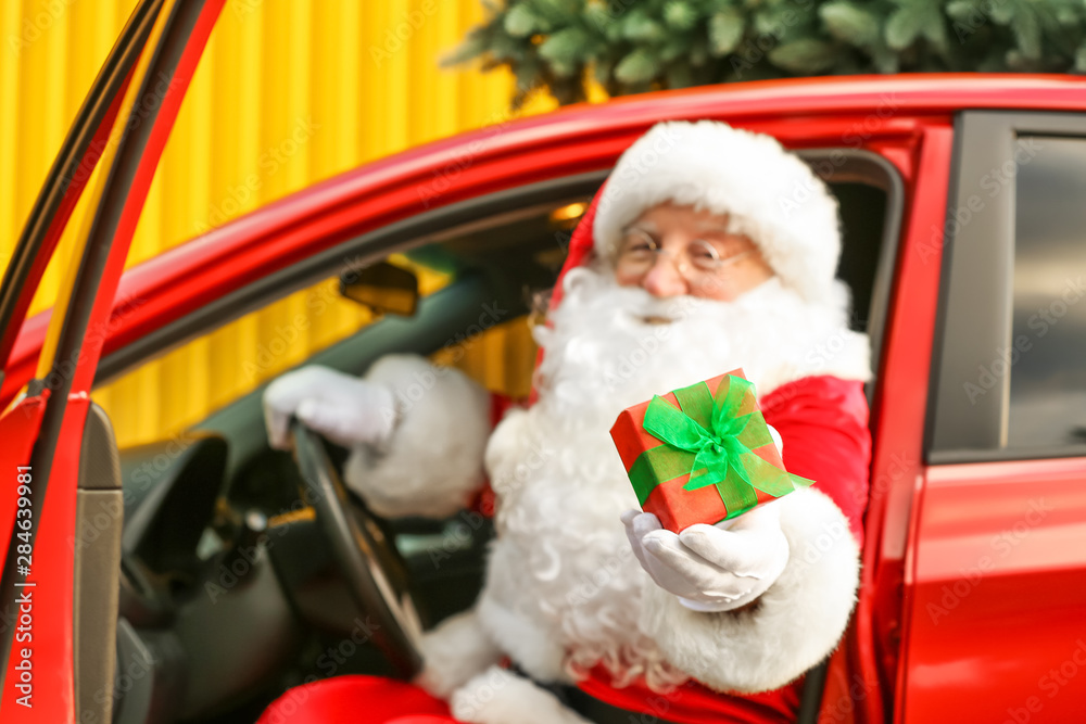 Santa Claus giving Christmas gift while sitting in car