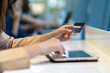 © THANANIT - Closeup Asian woman using credit card with tablet for online shopping in department store over the clothes shop store background, technology money wallet and online payment concept, credit card mockup