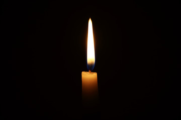 Burning candle in the dark with a dark background. Dark key photo.