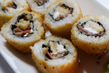 Fototapeta Maki - Sushi is traditionally made with medium-grain white rice. It is very often prepared with seafood, such as squid, eel, yellowtail, salmon, tuna or imitation crab meat.