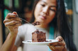 © anut21ng Stock - Asian woman eating chocolate cake at cafe