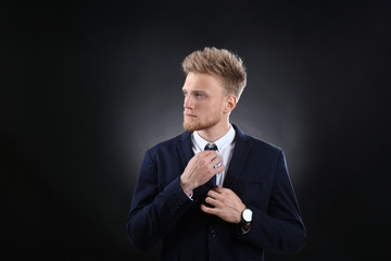 Wall Mural - Portrait of handsome young businessman on dark background