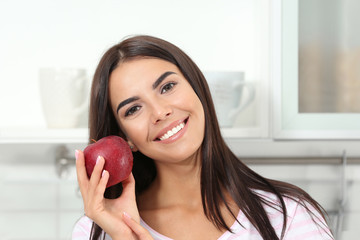 Sticker - Happy woman holding fresh apple in kitchen