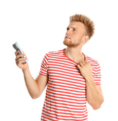 Poster - Young man with air conditioner remote suffering from heat on white background