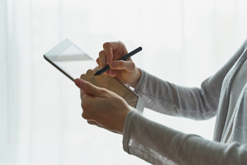 Woman holding tablet and writing on it, person with device side view closup