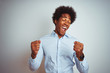 © Krakenimages.com - Young african american man with afro hair wearing elegant shirt over isolated white background very happy and excited doing winner gesture with arms raised, smiling and screaming for success.