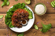 © lounom - Bo Luc Lac dish on wooden background. Also named Lok Lak in cambodia or Shaking Beef in America. Tasty marinated sauteed beef cubes are served with fresh lettuce, tomatoes, cucumbers, onions and rice