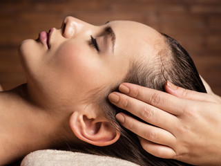 Masseur doing massage the head and hair for an woman in spa salon