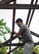 © tache - Man building wooden roof working with hammer
