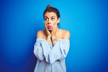 Poster - Young beautiful woman wearing bun hairstyle over blue isolated background Tired hands covering face, depression and sadness, upset and irritated for problem